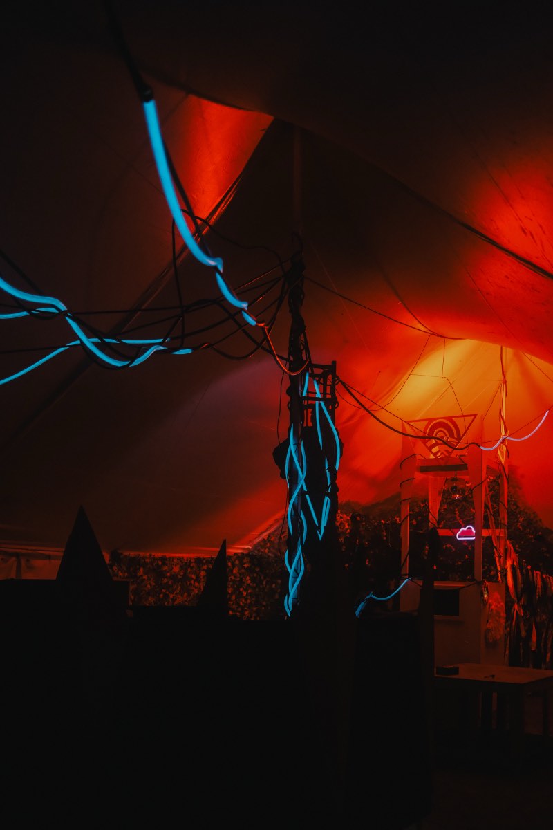 Blue lighting traces the central structure beneath an orange tent canopy