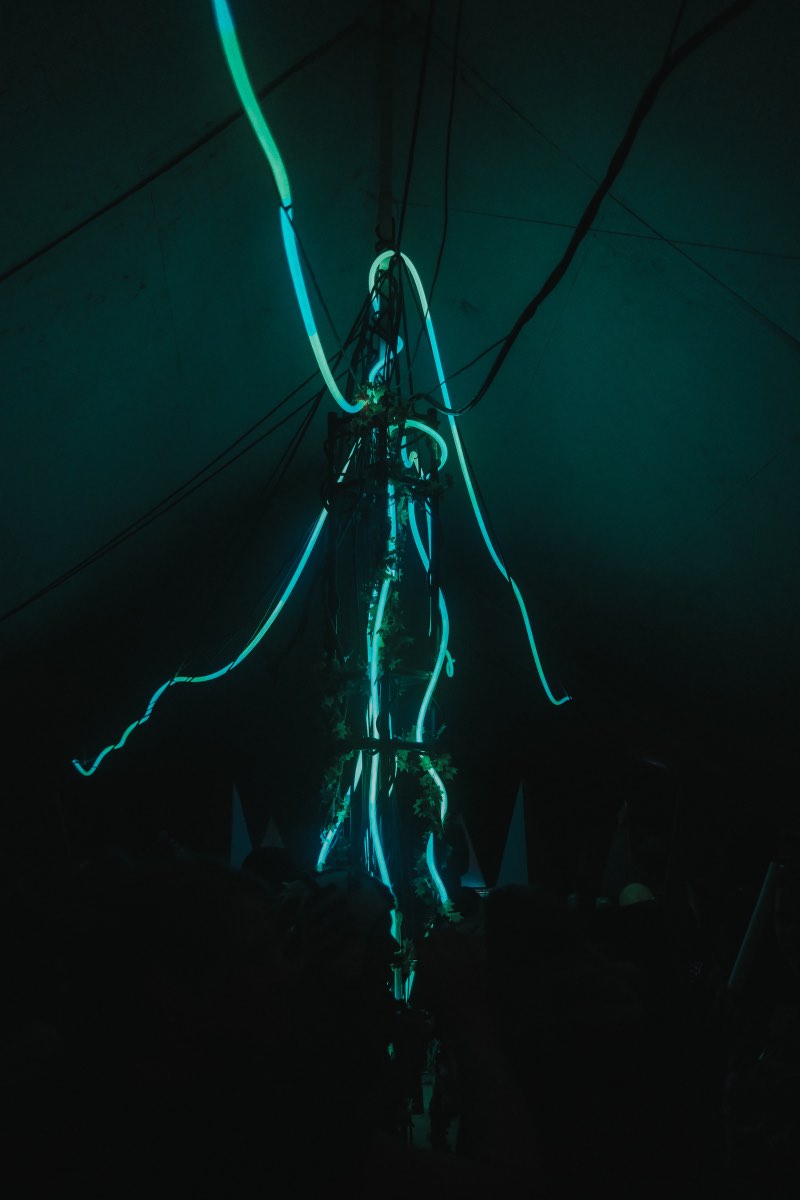 Teal lighting reveals the vertical structure and suspended tubes